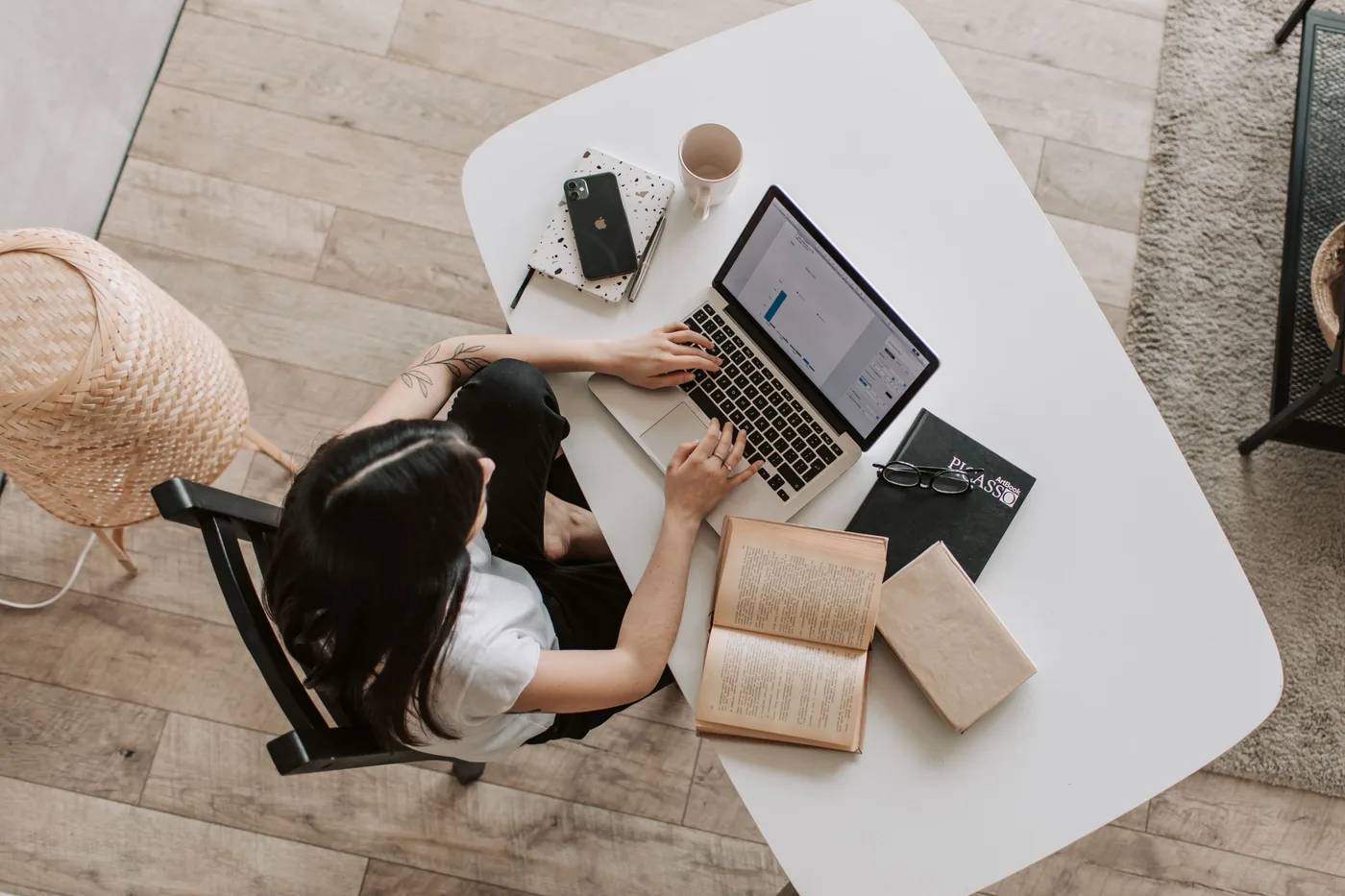 Person working on a laptop at a white desk at home
